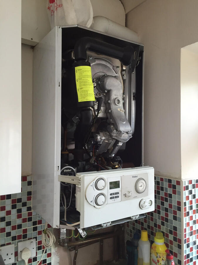 Professional plumber using tools to fix a boiler